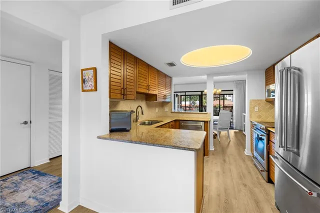 a view of a kitchen with kitchen island a sink appliances and a counter top space