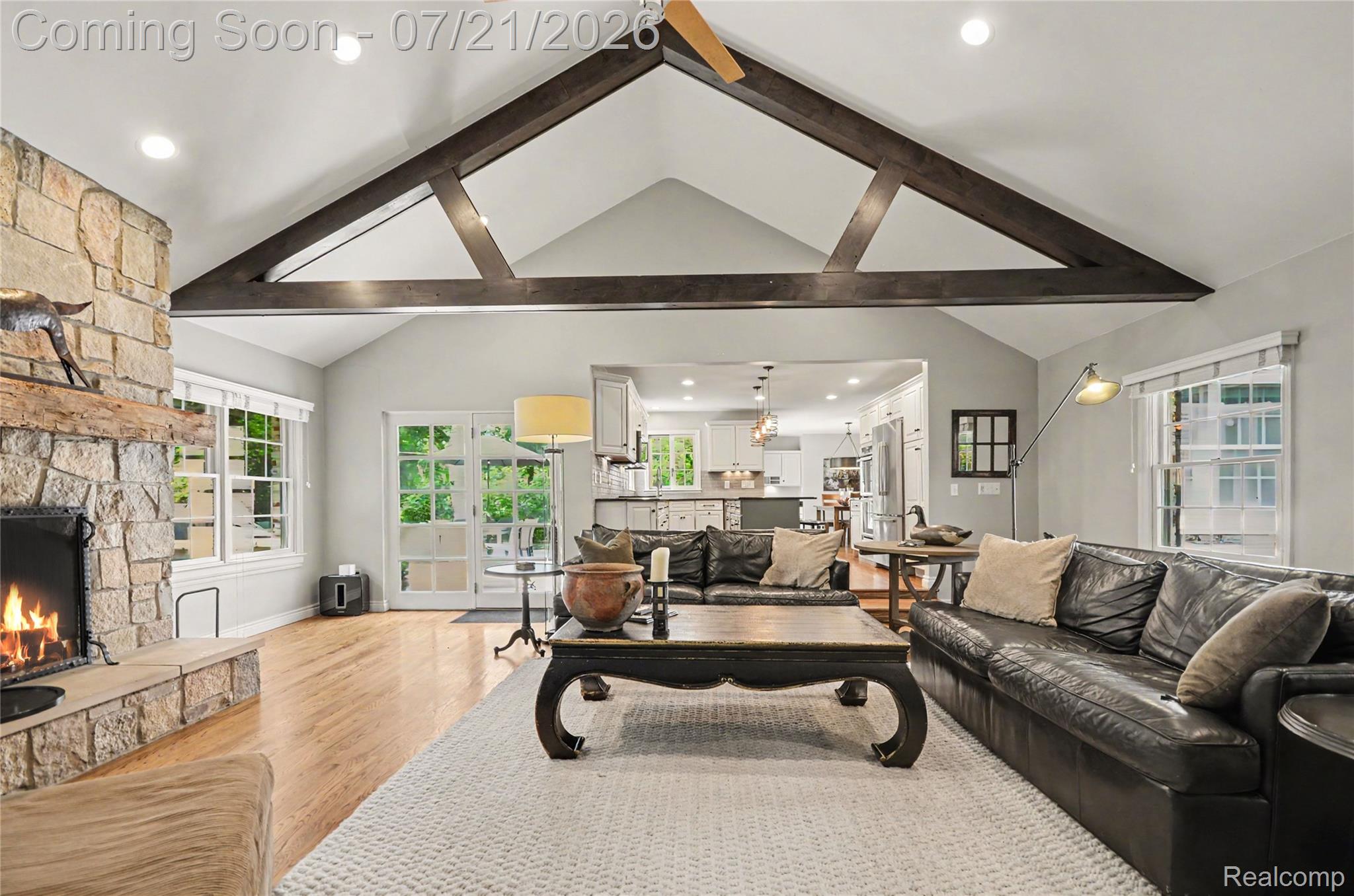 3780 Squirrel Road Bloomfield Hills, MI 48304 - Photo 9 of 59 Vaulted ceiling with exposed wood beams, stone fireplace, wood-finish flooring, recessed lighting, and French doors