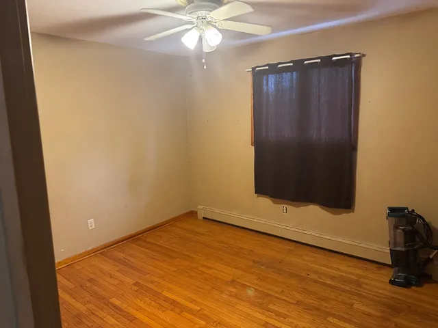 a view of an empty room with wooden floor and closet