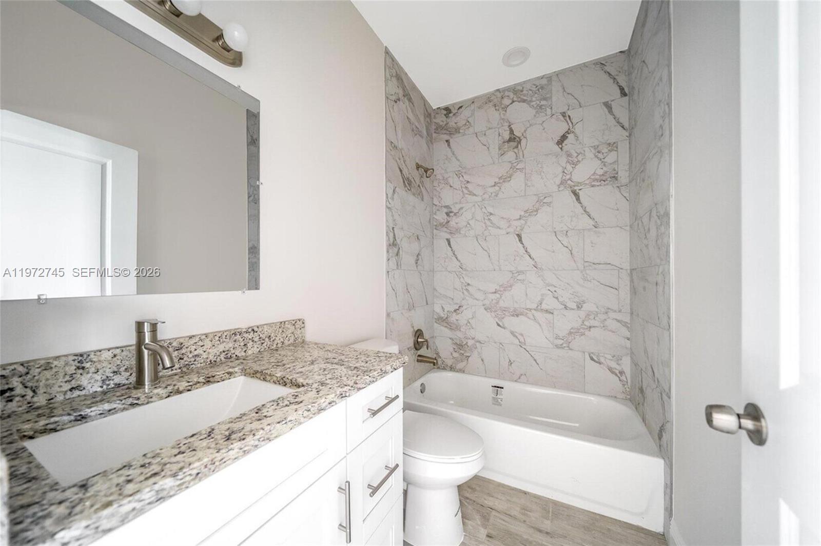 1538 West 26th Court Riviera Beach, FL 33404 - Photo 7 of 13 a bathroom with a granite countertop sink a toilet and bathtub