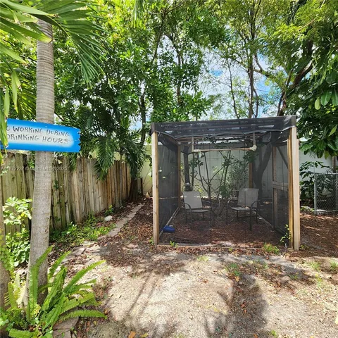 a view of a barn with large trees and wooden fence