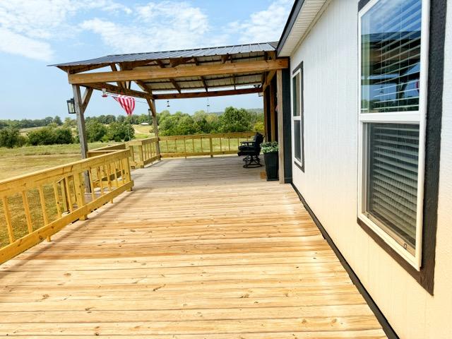 36469 1330th Road Wewoka, OK 74884 - Photo 21 of 39 Expansive wooden deck with a covered portion, featuring a metal roof and exposed wood beams