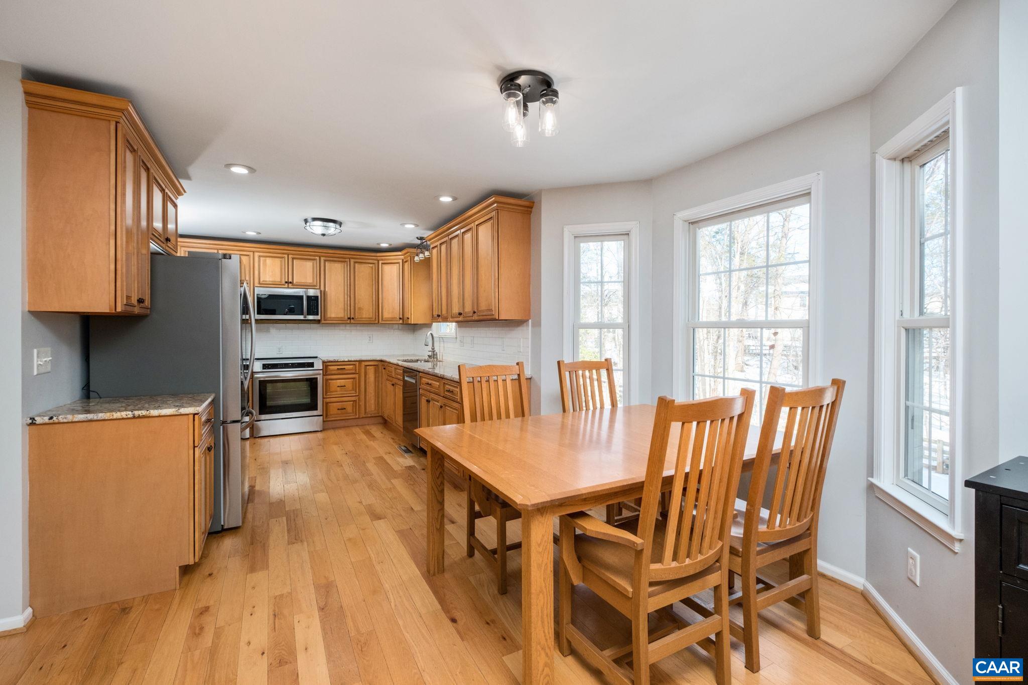 237 Spring Haven Lane Ruckersville, VA 22968 - Photo 4 of 41 a kitchen with stainless steel appliances granite countertop a stove a refrigerator a sink a dining table and chairs with wooden floor