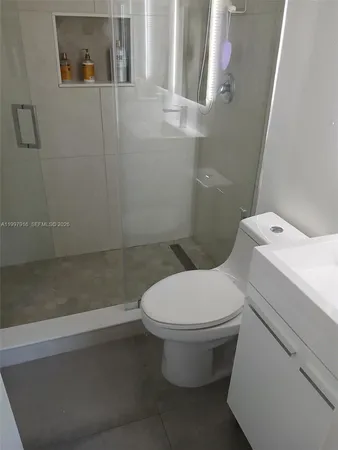 a white toilet sitting next to a bathroom sink and vanity