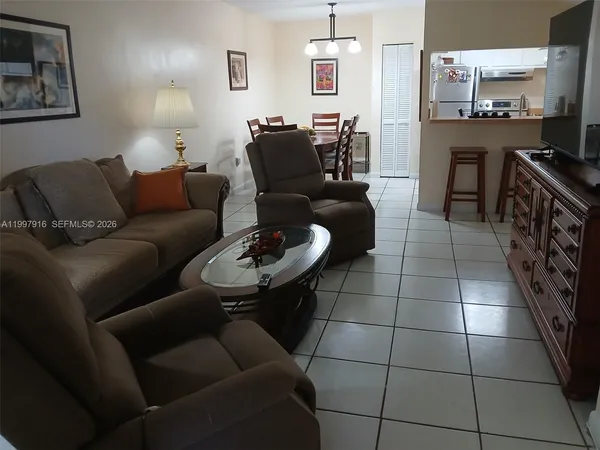 a living room with furniture a rug and kitchen view
