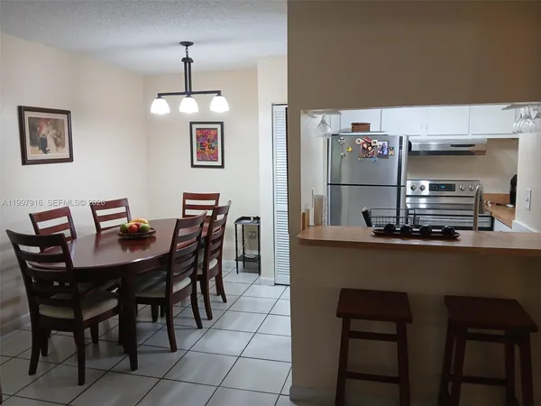 a dining room with stainless steel appliances a table chairs and a refrigerator