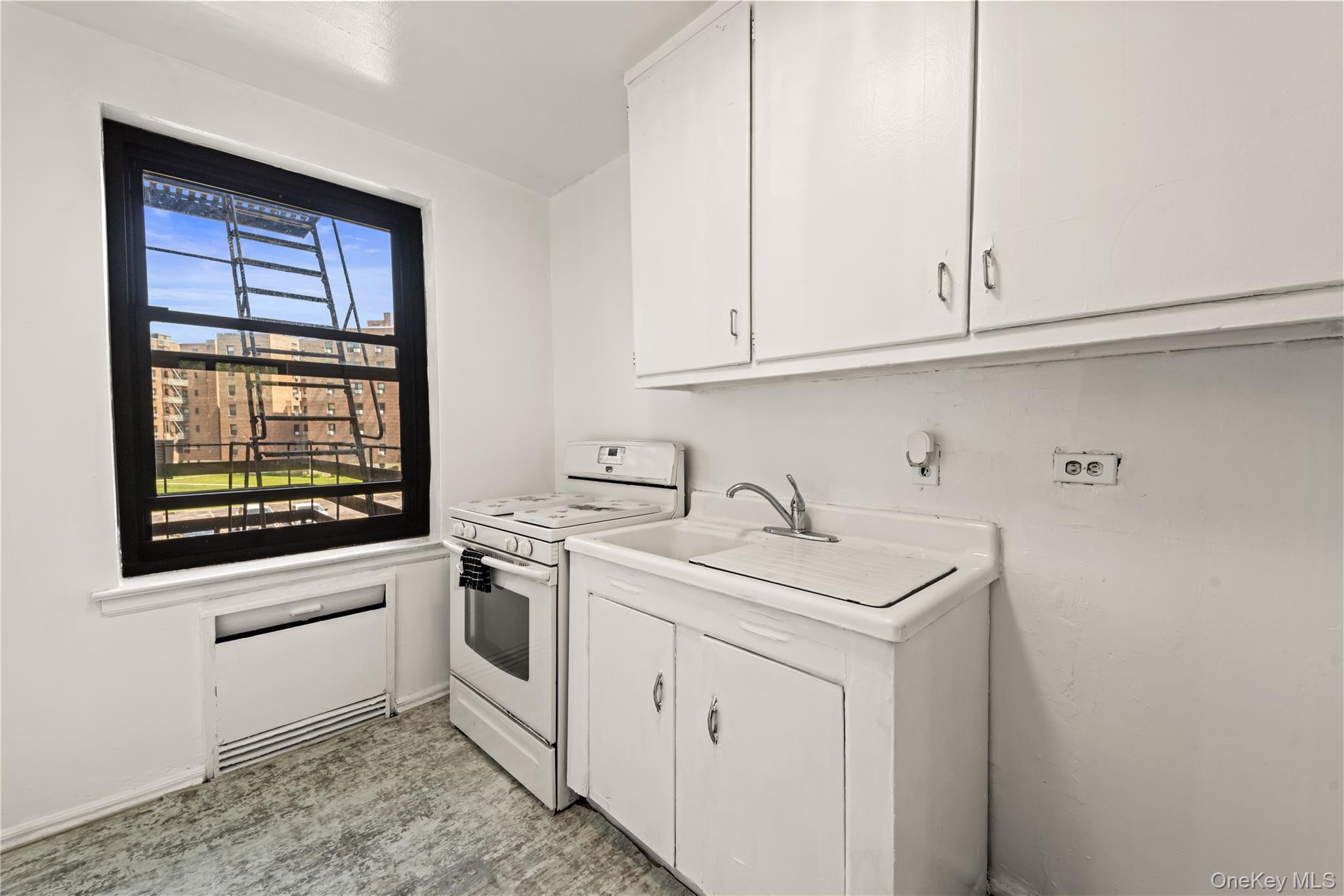 73-45 210th Street, Unit 3F Queens, NY 11364 - Photo 11 of 15 a kitchen with white cabinets and sink