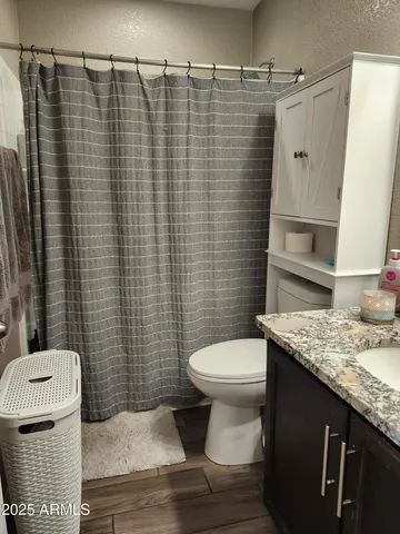 a view of a hallway to a room with wooden floor and cabinet