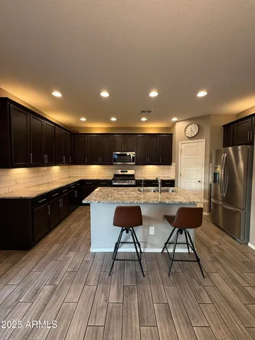 a kitchen with stainless steel appliances kitchen island granite countertop a refrigerator and a sink
