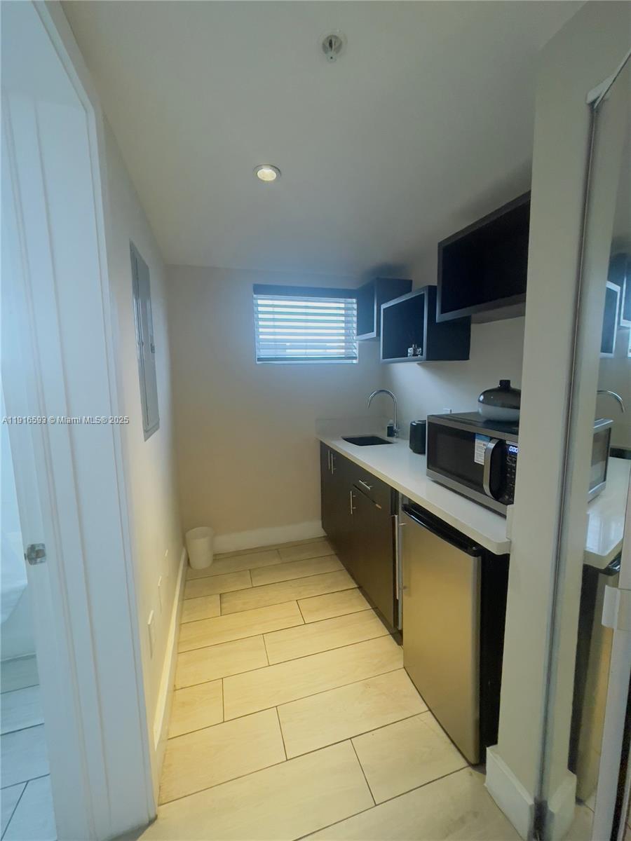 7310 Harding Avenue, Unit 318 Miami Beach, FL 33141 - Photo 5 of 6 a kitchen with stainless steel appliances granite countertop a sink and cabinets