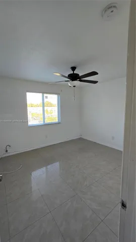 an empty room with a windows and ceiling fan