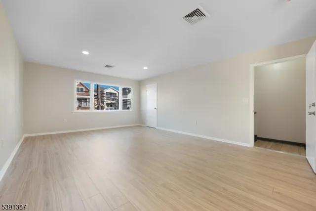 a view of an empty room with a window and wooden floor