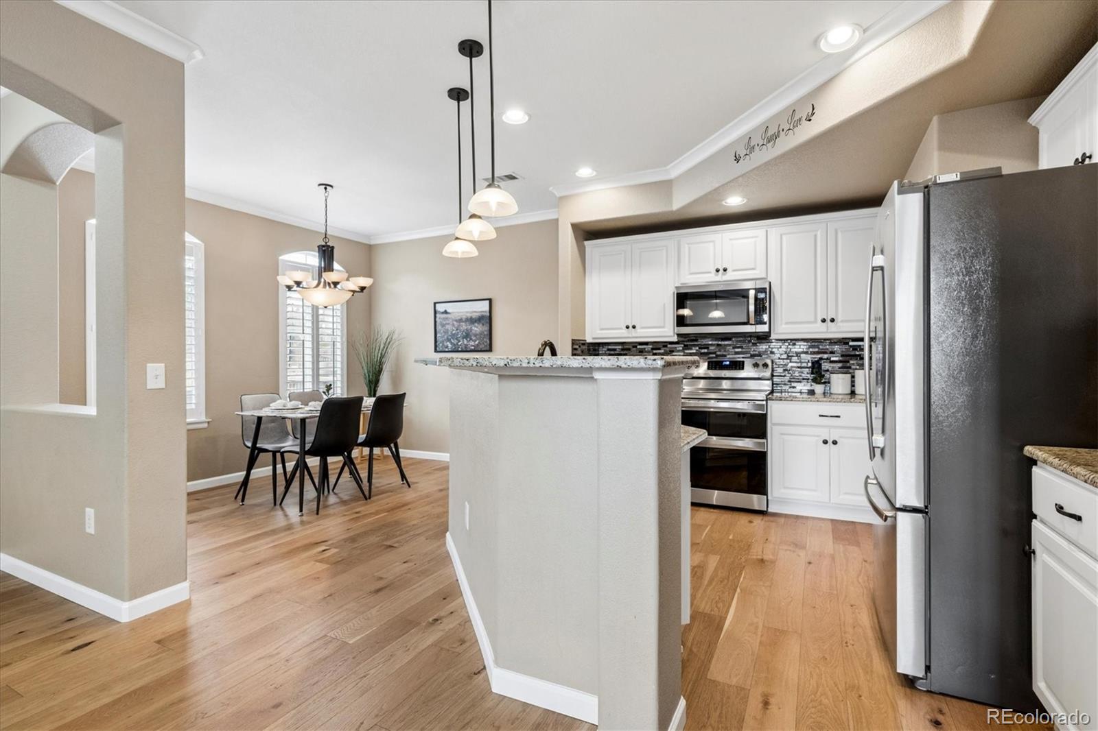 485 Elmhurst Way, Unit C Highlands Ranch, CO 80129 - Photo 15 of 42 a kitchen with stainless steel appliances kitchen island granite countertop a refrigerator a stove top oven a sink dishwasher a dining table and chairs with wooden floor