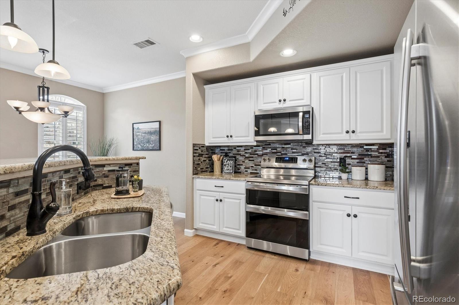 485 Elmhurst Way, Unit C Highlands Ranch, CO 80129 - Photo 21 of 42 a kitchen with granite countertop a sink stainless steel appliances and white cabinets