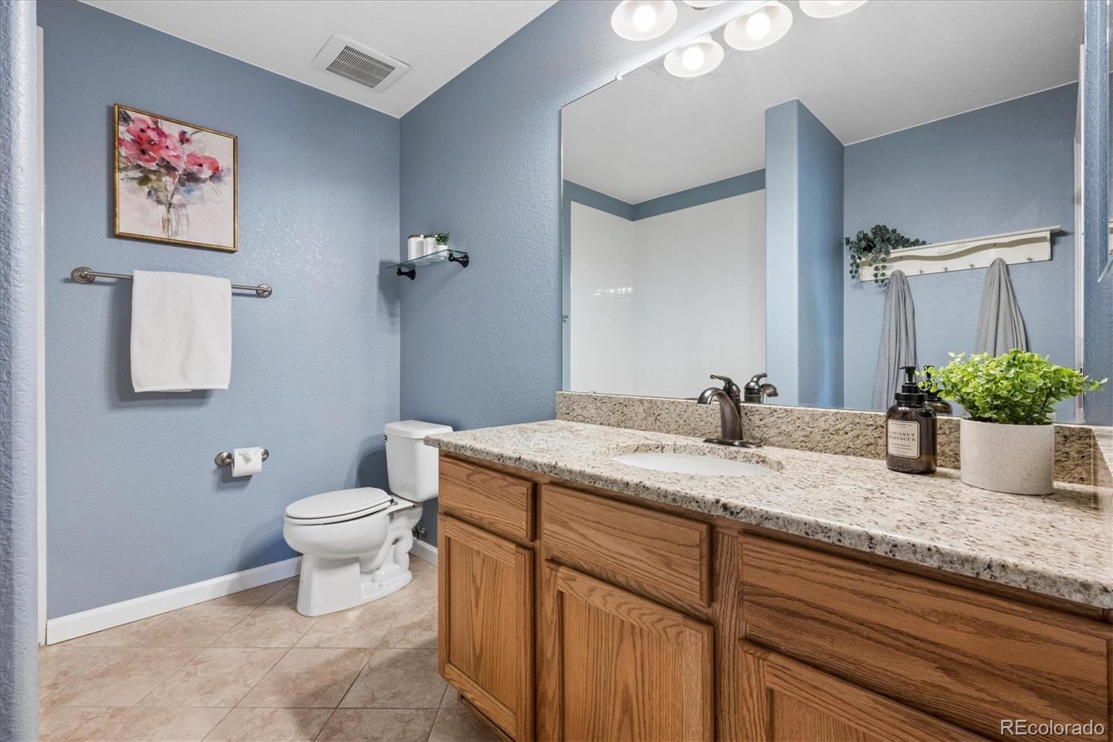 485 Elmhurst Way, Unit C Highlands Ranch, CO 80129 - Photo 25 of 42 a bathroom with a granite countertop sink a toilet and mirror