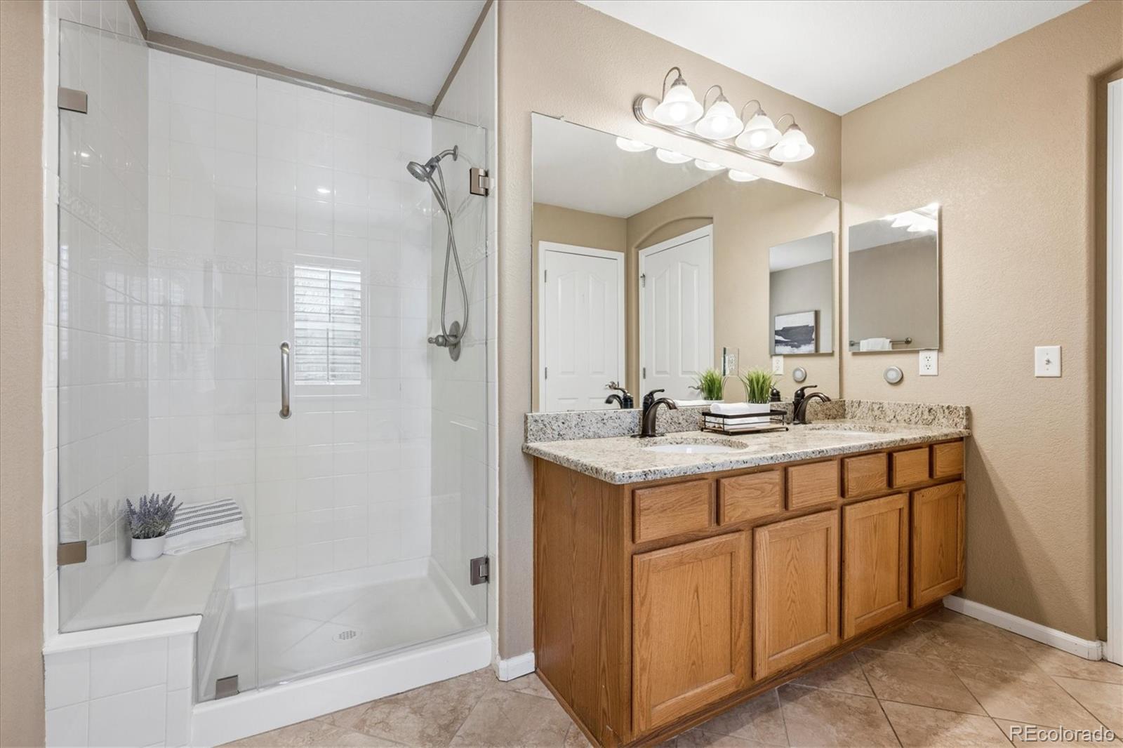 485 Elmhurst Way, Unit C Highlands Ranch, CO 80129 - Photo 34 of 42 a bathroom with a shower sink vanity and mirror
