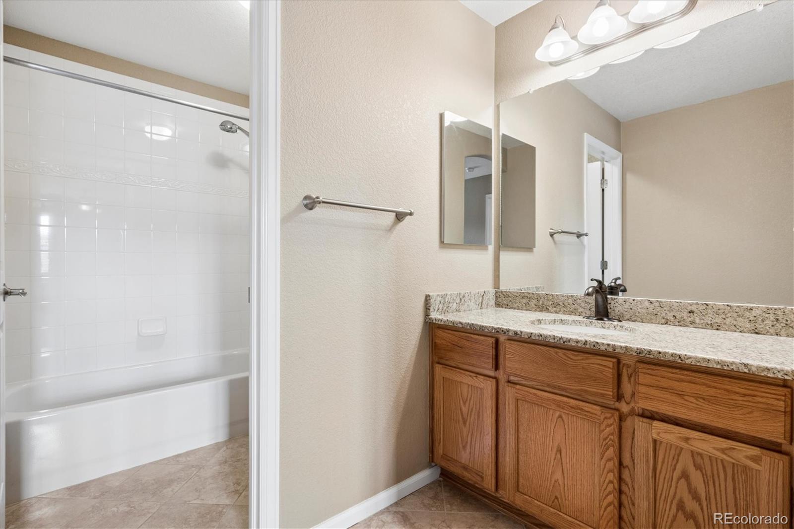 485 Elmhurst Way, Unit C Highlands Ranch, CO 80129 - Photo 38 of 42 a bathroom with a granite countertop sink and a mirror