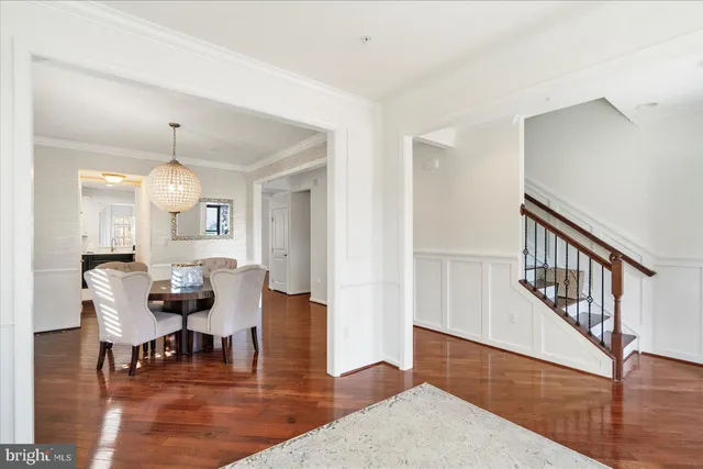 a dining room with wooden floor a chandelier a glass table and chairs