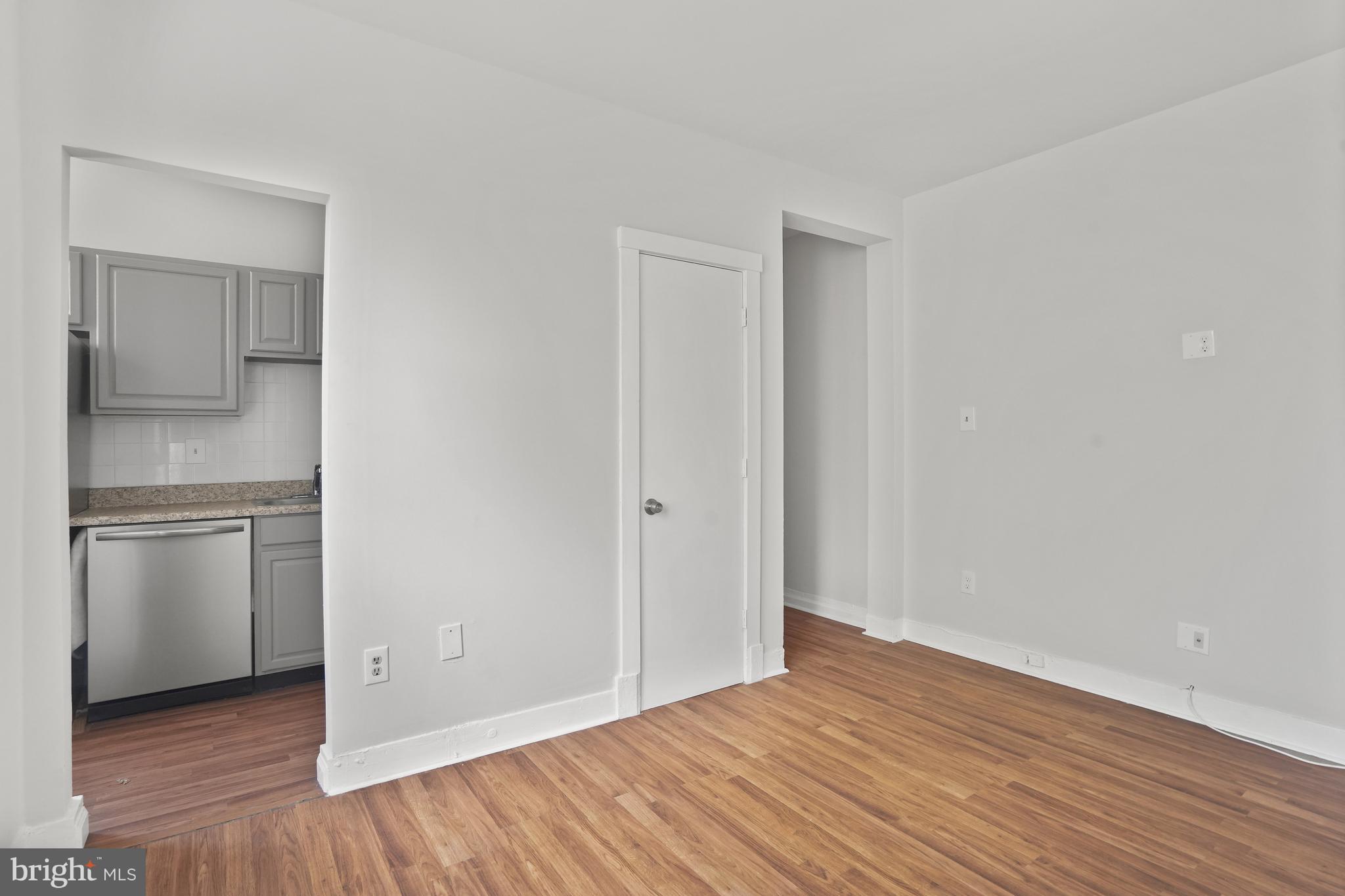 7 18th Street Southeast, Unit 208 Washington, DC 20003 - Photo 4 of 21 a view of an empty room with wooden floor and a kitchen