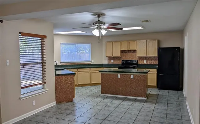 a kitchen with granite countertop a refrigerator a sink a stove and cabinets