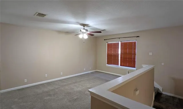 an empty room with windows and fan