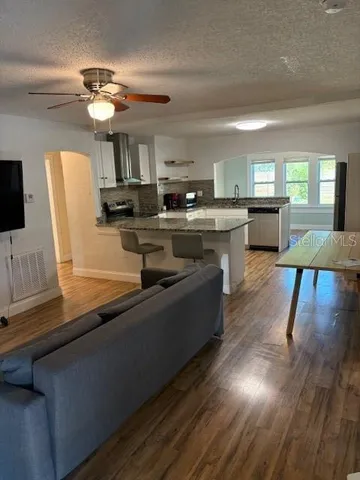 a kitchen with stainless steel appliances granite countertop a refrigerator a sink dishwasher a stove and a dining table with wooden floor