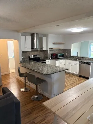 a kitchen with kitchen island granite countertop a sink cabinets and wooden floor