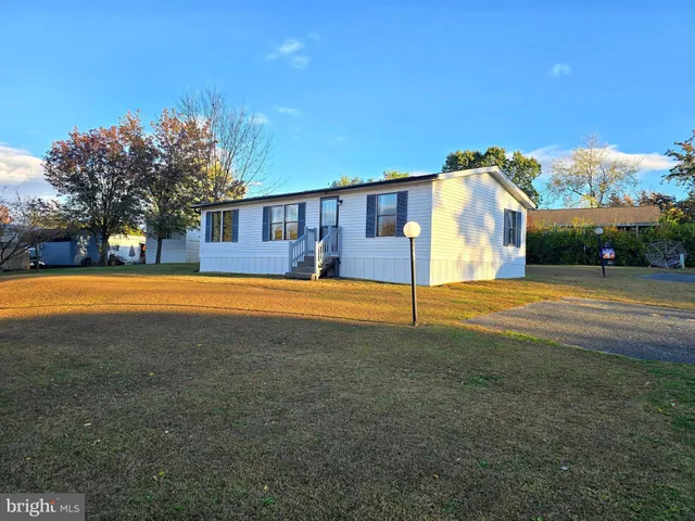 a view of a house with a big yard and large trees