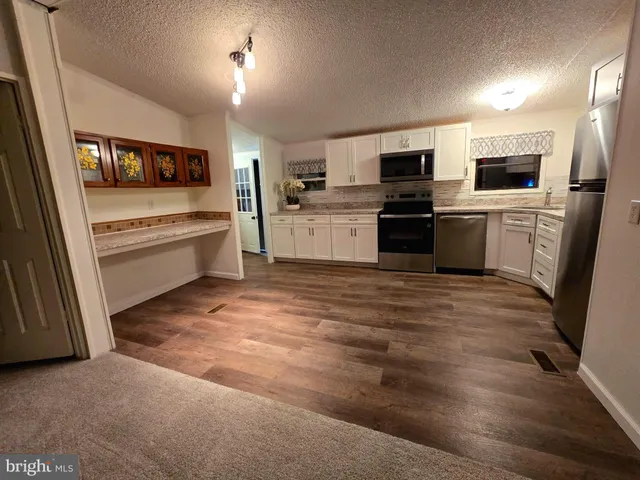 a kitchen with stainless steel appliances kitchen island granite countertop a refrigerator and a stove top oven