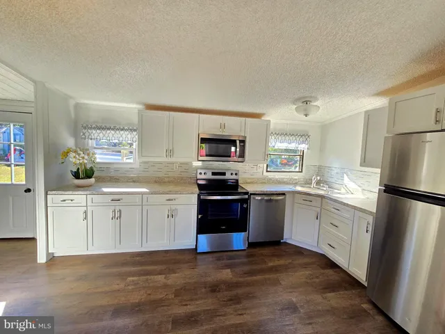 a kitchen with granite countertop a refrigerator stove top oven and sink