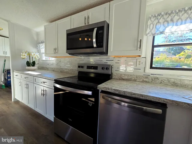 a kitchen with stainless steel appliances granite countertop a sink a stove a microwave and wooden cabinets