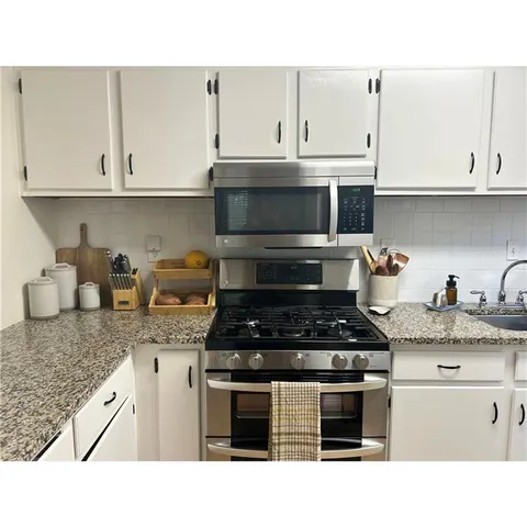 a kitchen with granite countertop white cabinets and stainless steel appliances