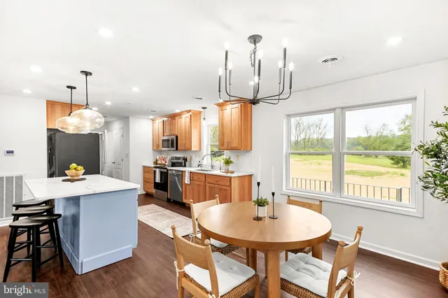 a room with stainless steel appliances a table chairs and a kitchen view