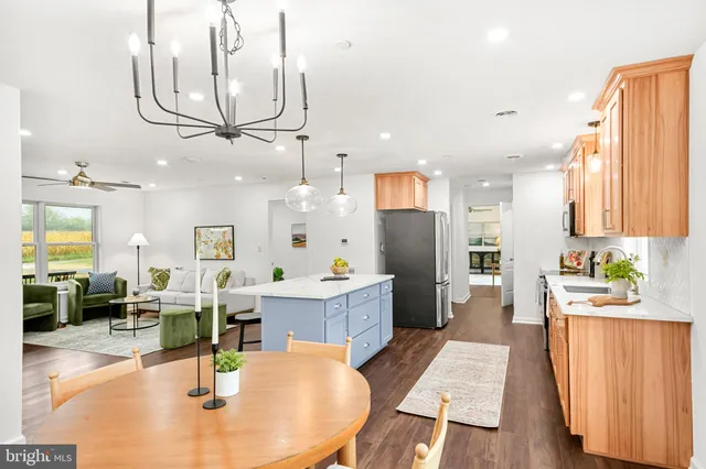 a living room with stainless steel appliances kitchen island granite countertop furniture and a chandelier