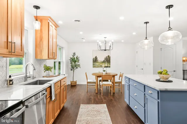 a kitchen with stainless steel appliances granite countertop a sink a stove and a wooden floors