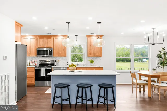 a kitchen with stainless steel appliances a dining table chairs stove refrigerator and sink