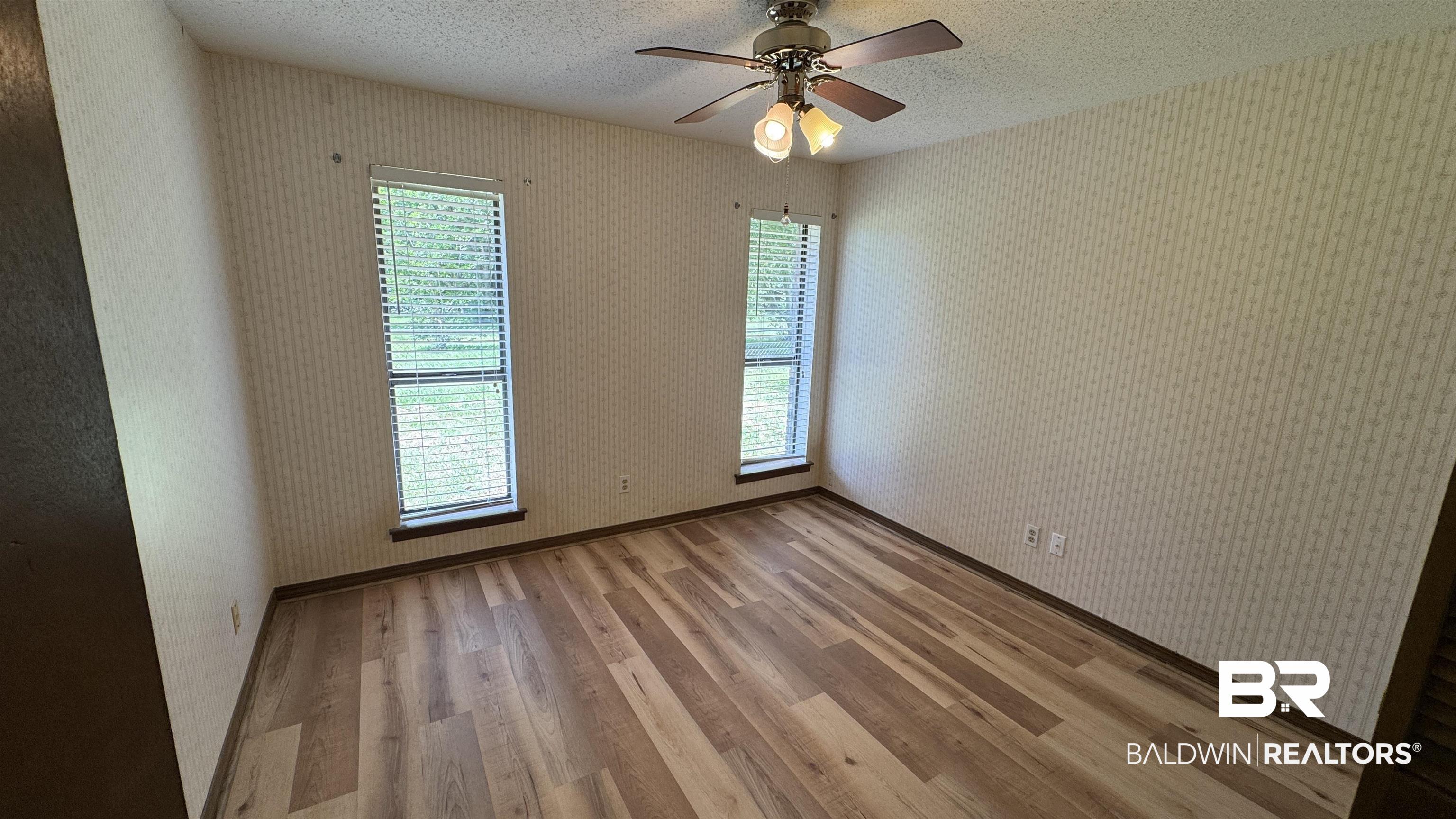 33370 Highway 98 Lillian, AL 36549 - Photo 35 of 58 Room featuring wood-finish flooring, patterned wallpaper, and two vertical windows with blinds