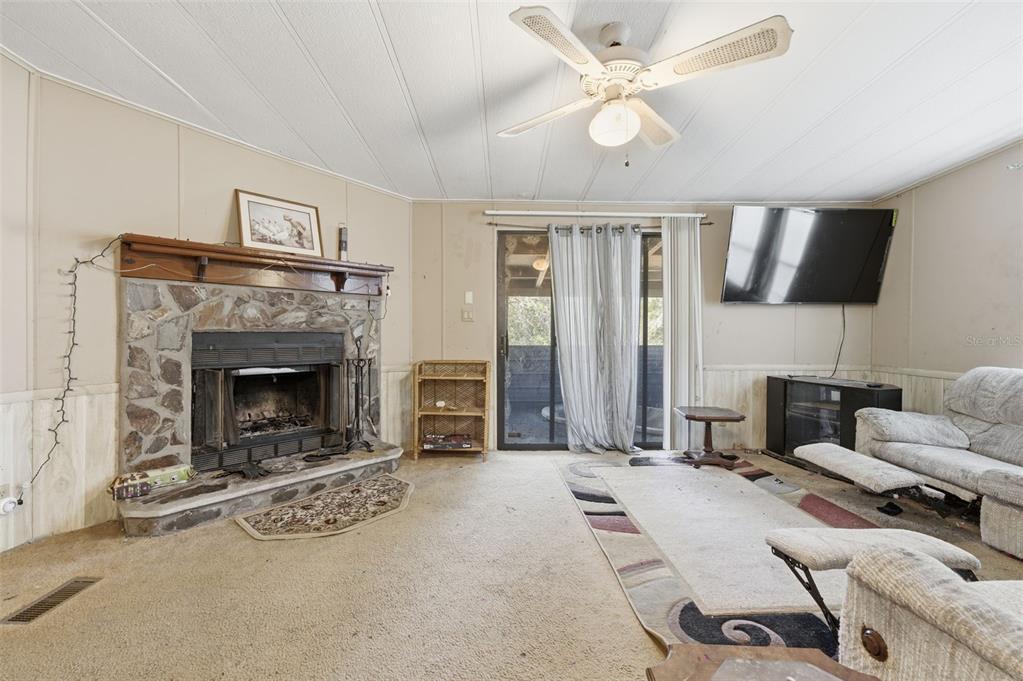 8045 Indian Trail Road Weeki Wachee, FL 34613 - Photo 15 of 49 a living room with furniture a fireplace and a flat screen tv