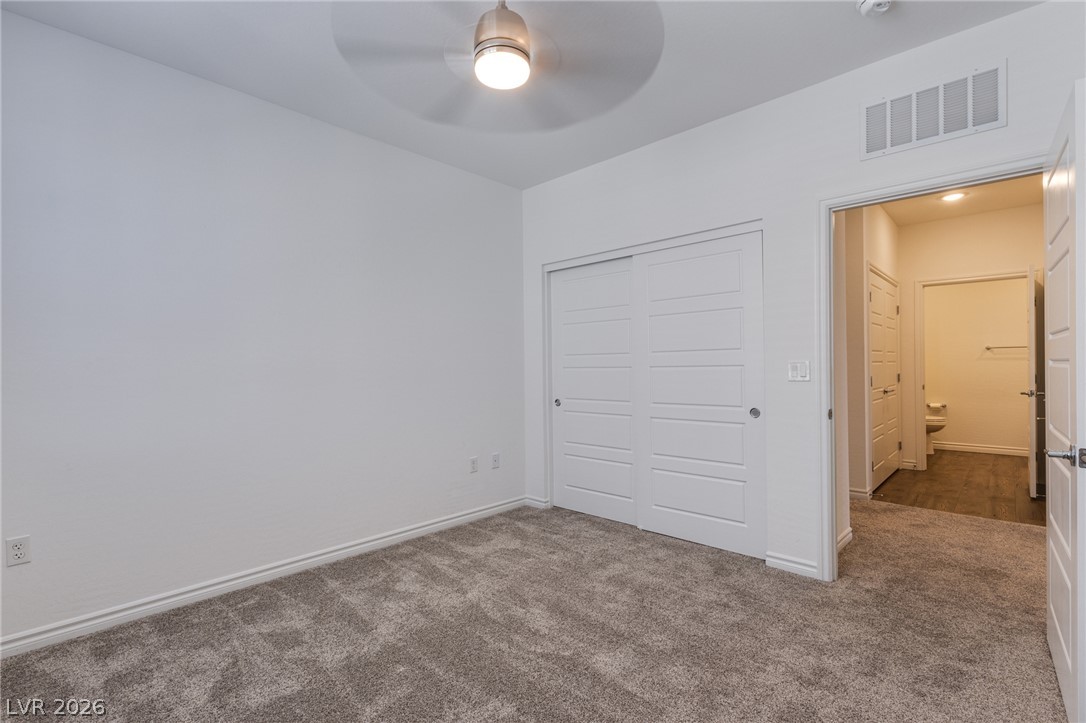 2555 Hampton Road, Unit 8206 Henderson, NV 89052 - Photo 14 of 25 A well-lit bedroom with neutral carpet flooring and ample closet space, connecting to an adjacent bathroom.