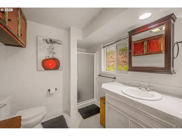 a bathroom with a sink a mirror a toilet and a window