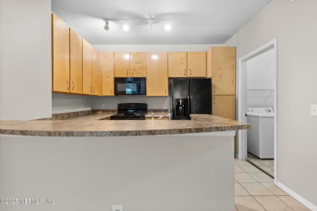 a kitchen with kitchen island granite countertop stainless steel appliances a sink a refrigerator a stove a microwave and island