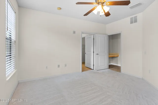 an empty room with chandelier fan and windows