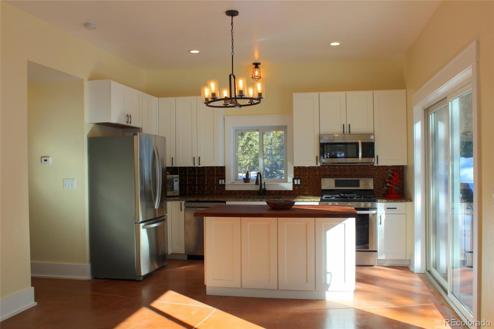 4147 Campfire Road Hartsel, CO 80449 - Photo 4 of 27 a kitchen with stainless steel appliances granite countertop a refrigerator a stove a sink dishwasher a refrigerator and white cabinets with wooden floor