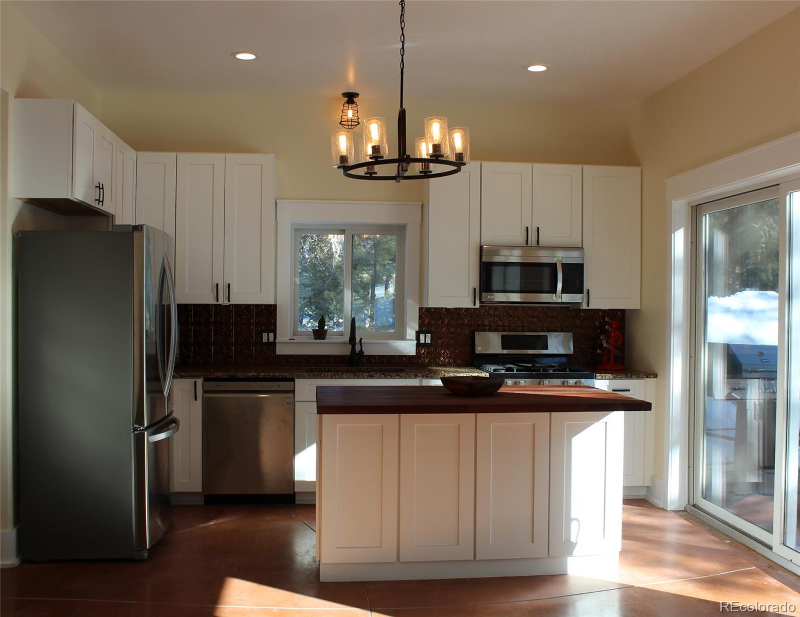 4147 Campfire Road Hartsel, CO 80449 - Photo 5 of 27 a kitchen with kitchen island granite countertop stainless steel appliances a stove refrigerator a sink and microwave