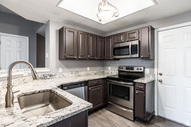 900 Bitner Road, Unit M 17 Park City, UT 84098 - Photo 3 of 29 Kitchen featuring stainless steel appliances, dark wood finish cabinets, light wood-style flooring, and light stone countertops