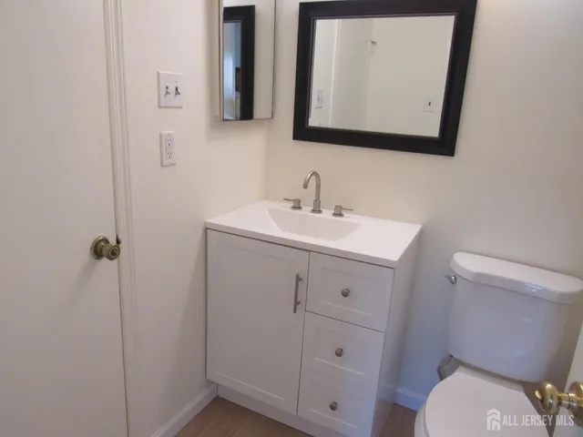 a bathroom with a toilet sink vanity and mirror