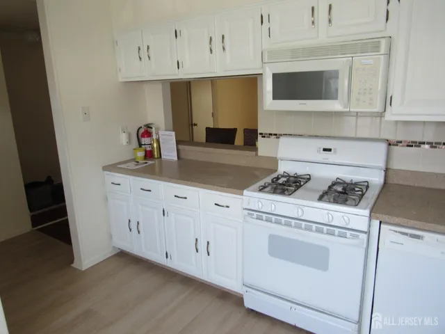 a kitchen with white cabinets and white appliances