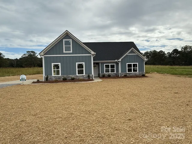 a front view of a house with yard and large trees