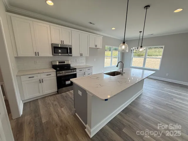 a kitchen with kitchen island a stove a sink a center island and wooden floor