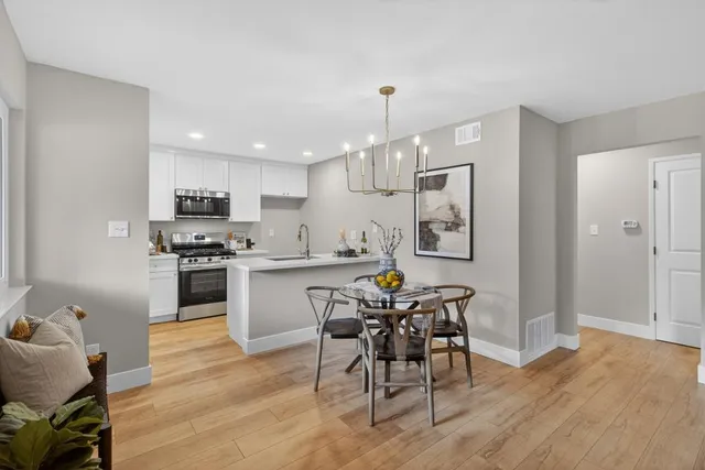 a kitchen with stainless steel appliances a dining table chairs stove and refrigerator